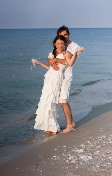 Молодая пара в белой одежде на пляже — стоковое фото