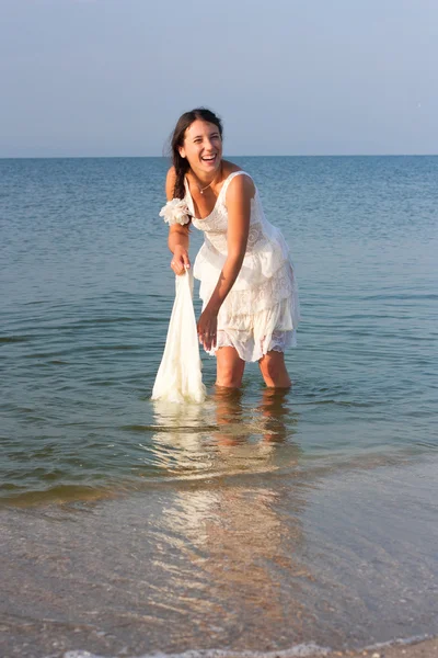 Young brunet woman in the blue water in wet white dress