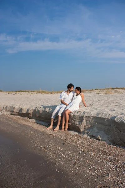 Młoda para zakochana siedzi na plaży — Zdjęcie stockowe