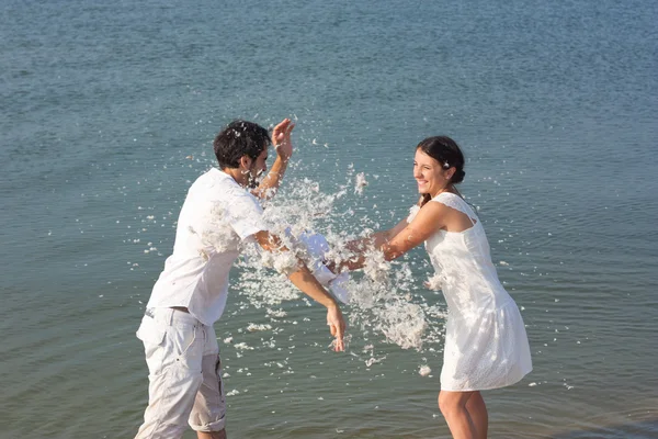 Joven pareja luchando almohadas en la playa —  Fotos de Stock