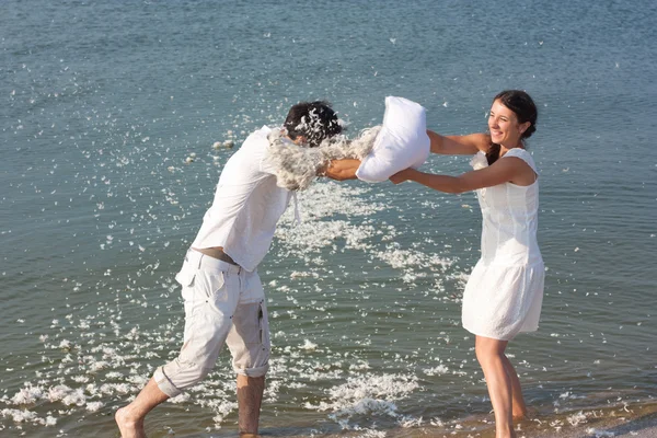 Young couple fighting pillows on the beach — Stock Photo, Image