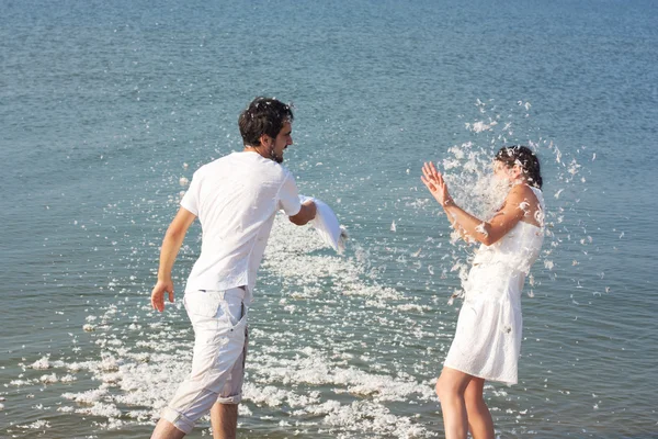 Young couple fighting pillows on the beach — Stock Photo, Image