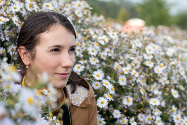 Beautiful young brunette woman in white flowers outdoors — Stock Photo, Image