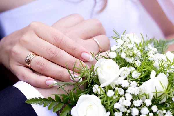Mani con fedi nuziali e bouquet da sposa — Foto Stock