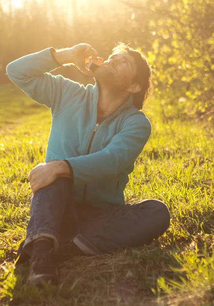 Man zit op gras en gebruik mobiele telefoon — Stockfoto