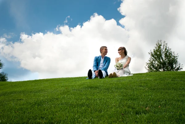 Recién casados en un césped verde de fondo el cielo — Foto de Stock