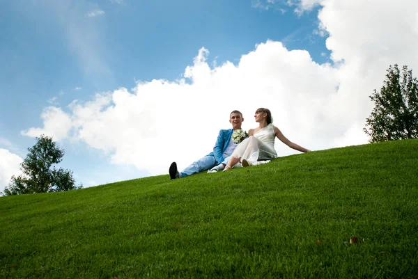 Nowożeńcy na zielony trawnik tło nieba — Zdjęcie stockowe