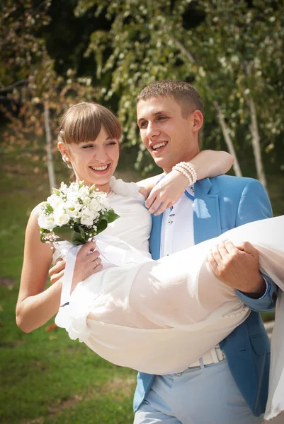 Bruidegom draagt zijn bruid in de armen — Stockfoto