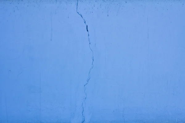 Текстурная синяя стена с трещиной — стоковое фото