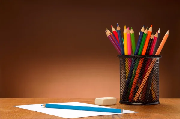 Hoja en blanco de papel y lápices de colores sobre una mesa de madera — Foto de Stock