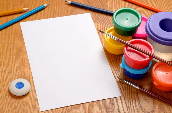 Foglio di carta bianco con matite e vernici colorate — Foto Stock