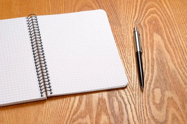 Un cuaderno blanco con bolígrafo negro sobre mesa de madera —  Fotos de Stock