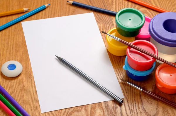 Foglio di carta bianco con matite e vernici colorate — Foto Stock