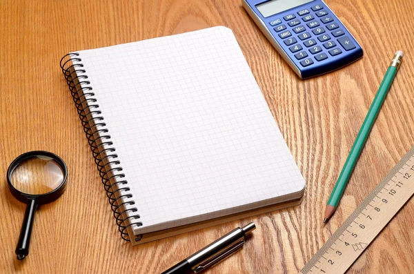 Desk with sheet of paper, calculator and stationery objects seen from above — Stock Photo, Image