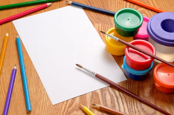 Foglio di carta bianco con matite e vernici colorate — Foto Stock