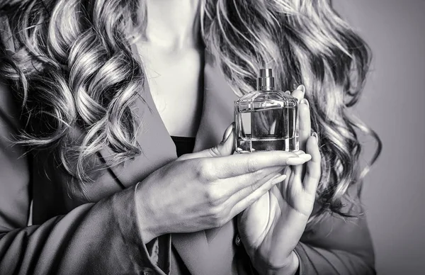 Kobieta w sprayu perfum ma aromat. Kobieta trzymająca butelkę perfum. Kobieta prezentuje zapach perfum. Czerń i biel — Zdjęcie stockowe