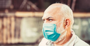 Coronavirus, hastalık, enfeksiyon, karantina, tıbbi maske. Yüz maskesi takan yaşlı bir adam. Tıbbi maske takmış yaşlı bir adamın portresi. Yaşlılar için koronavirüs tehlikesini kavrayın.