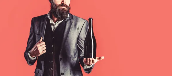 Kırmızı şarap şişesini elinde tutan kişi. Şampanya ve şarap taşıyan bir adam. Sakallı adam elinde bir şişe şampanya ve camla — Stok fotoğraf