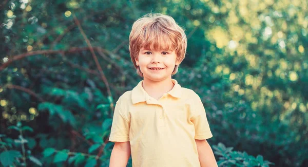 Barn utomhus i naturen. Lyckligt barn. Rolig liten pojke isolerad på en bakgrund av gröna träd. En leende pojke. Gladlynt barn. Lyckliga barn pojke — Stockfoto