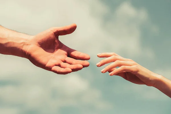Yardım eli uzatıyorum. Mavi gökyüzü arka planında kadın ve erkeğin elleri. Yardım eli uzatıyorum. Dayanışma, şefkat ve yardım, kurtuluş.