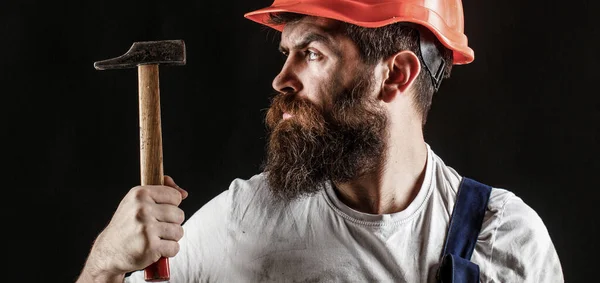 Handyman diensten. industrie, technologie, bouwer man, concept. Een man met baard, helm, helm, hoed. Hamer hameren. Bouwer in helm, hamer, klusjesman — Stockfoto