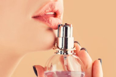 Kadın parfüm şişesi. Seksi dudaklar. Pembe dudak. Koyu kırmızı rujlu, tombul, seksi dudaklara yakın çekim. Parfüm kullanan güzel bir kız. Parfüm şişesi olan kadın. Kadın parfüm sunar.