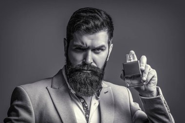 Erkeksi parfüm, takım elbiseli sakallı adam. Elinde parfüm şişesi tutan bir erkek. Erkek parfümü, parfüm. Parfüm ya da parfüm şişesi, parfüm, kozmetik, parfüm şişesi, kolonya tutan erkek.