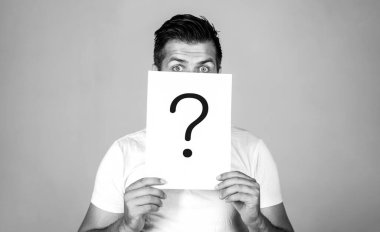 Soru işareti, sembol. Düşünceli erkek. Adam bir soru. Şüpheli adam soru işareti tutarak. Sorunlar ve çözümleri. Yanıt almaya. Adam, arkasında sorgulama sembolü bakmak portresi. İzole erkek