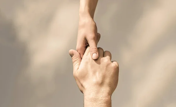 Les mains de l'homme et de la femme se touchent, se soutiennent. Solidarité, compassion, charité, sauvetage. Un coup de main. Mains d'homme et de femme sur fond de ciel bleu. Prêter main forte — Photo