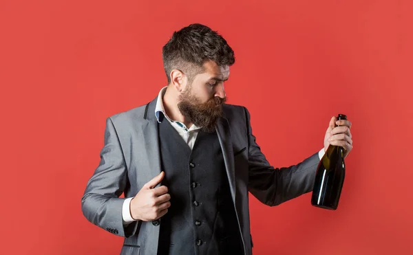 Brodatego z butelką szampana i szklanką. Osoba trzyma w ręku czerwoną butelkę wina. Mężczyzna trzyma butelkę z szampanem, wino — Zdjęcie stockowe