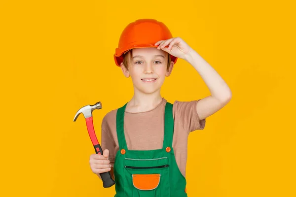 Kinderhelm, harde hoed. Hamer hameren. Kleine bouwer in helm en gezoem. Kind verkleed als arbeider bouwer. Kleine jongen met een helm op. Portret kleine bouwer in harde hoeden hamer — Stockfoto