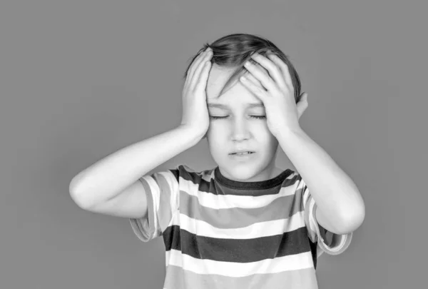 Hoofdpijnlijk kind. Lijdende migraine. Hoofdpijn door stress. Portret van een droevige jongen die zijn hoofd vasthoudt met zijn hand, geïsoleerd op de rode achtergrond. Kleine jongen heeft hoofdpijn. Wanhoop, tragedie — Stockfoto