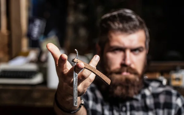 Mens haircut. Man in barbershop. Handsome bearded hairdresser is holding a straight razor while barbershop. Straight razor, barbershop, beard. Portrait of brutal bearded man. Vintage straight razor — Stock Photo, Image