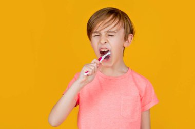 Küçük adam dişlerini fırçalıyor. Diş fırçalı mutlu çocuk. Sağlık hizmeti, diş hijyeni. Küçük çocuk diş fırçasıyla diş temizliyor. Diş hijyeni.