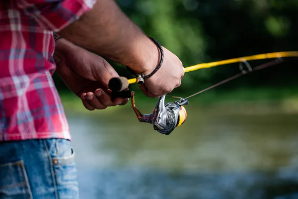 Bobine de pêche. Tige de pêche avec bobine de corps en aluminium. Équipement de pêche. Fournitures et équipement pour poissons. Pêche bobine gros plan sur le fond de la rivière — Photo