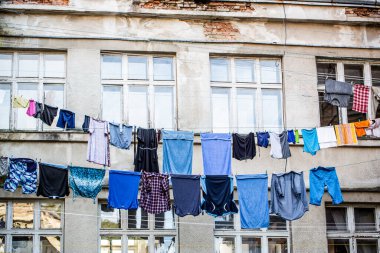 Eski bir evin dışında çamaşır yıkadım. Çamaşırları kurutuyordum. Temiz giysiler dışarıda kuruyor. Elbiseler çamaşır ipinde kurumaya bırakılmış.