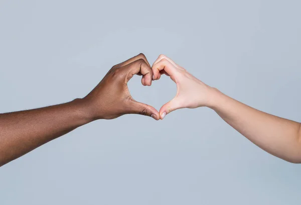Las personas de diferentes colores de piel ponen sus manos juntas haciendo que la forma del corazón en fondo blanco. Caridad, amor y diversidad: primer plano de las manos femeninas y masculinas de diferentes colores de piel que dan forma al corazón — Foto de Stock