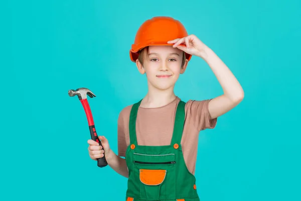 Kind verkleed als arbeider bouwer. Kleine jongen met een helm op. Portret kleine bouwer in harde hoeden hamer. Kinderhelm, harde hoed. Hamer hameren — Stockfoto