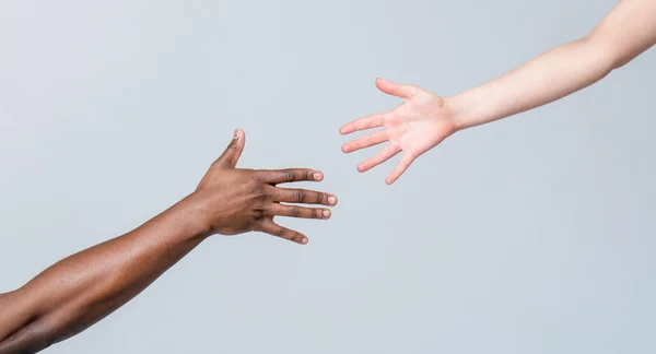 Допомога іншій людині. Жінка і африканка. Допомагає, рятує, мультифонізує людей. Допомагати руки, рятувати жест. Чорно-білі людські руки. Африканські й кавказькі руки — стокове фото