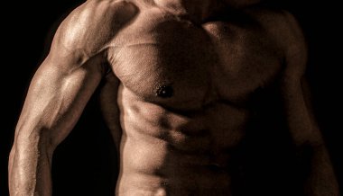 Gövde kasları yakın. Gövdesi olan kaslı seksi bir adam. Siyah arka planda kaslı bir spor mankeni. Çıplak, güçlü kaslı, şehvetli bir adam.