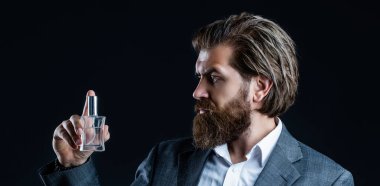 Erkek parfümü, takım elbiseli sakallı bir adam. Elinde parfüm şişesi tutan bir erkek. Erkek parfümü, parfüm. Parfüm ya da parfüm şişesi ve parfüm, kozmetik, parfüm şişesi, kolonya tutan erkek.