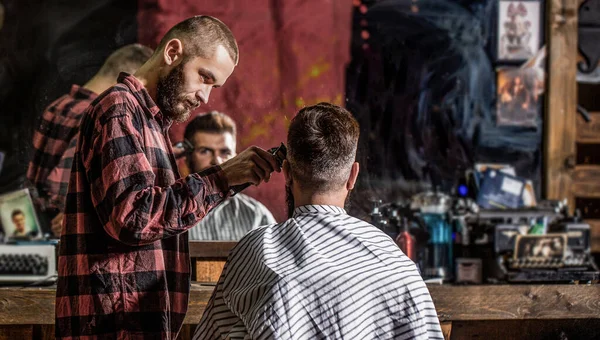 Hands of barber with hair clipper, close up. Bearded man in barbershop. Haircut concept. Man visiting hairstylist in barbershop. Barber works with hair clipper. Hipster client getting haircut — Stock Photo, Image