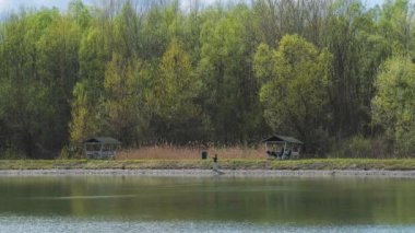 Fisherman, lake, forest. Fisherman in his hand holding spinning. Fishing, spinning reel, fish, Breg rivers, fishing. Fisherman standing on the shore of lake with fishing rod. Man fishing on a lake.