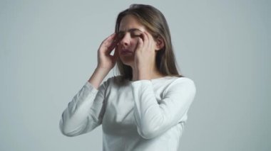Esmer kadın gri arka planda stres hissederek şakaklarına dokunuyor. Baş ağrısı çeken kadın çaresiz, acı ve migren yüzünden stresli. Şiddetli baş ağrısı olan bir kadın el ele tutuşuyor.