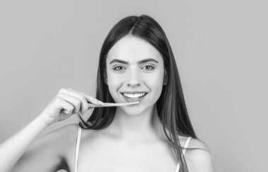 Young beautiful girl holding a toothbrush. The concept of a healthy lifestyle. Dental hygiene. Happy girl brushing her teeth. Black and white