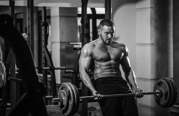 Athletic man with six pack, perfect abs. Close up training with barbell. Man lifting barbells working out in gym. Closeup deadlift barbells workout. Workout the gym