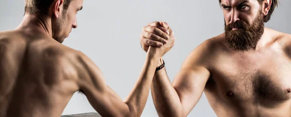 Two mans hands clasped arm wrestling, strong and weak, unequal match. Arm wrestling. Heavily muscled bearded man arm wrestling a puny weak man. Arms wrestling thin hand, big strong arm in studio — Stock Photo, Image