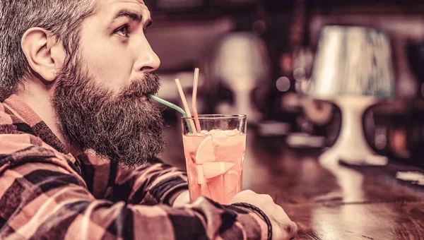 Tropikalny koktajl alkoholowy. Barman w pubie lub restauracji. Koktajl dla brodatych. Portrecista, pijący sok pomarańczowy. Człowiek brodaty pije koktajle — Zdjęcie stockowe