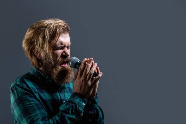 Erkek karaokeye katılıyor. Sakallı adam mikrofonla şarkı söylüyor. Erkek, mikrofonla şarkı söylüyor. Elinde mikrofon olan ve şarkı söyleyen sakallı bir adam. Karaokedeki sakallı adam mikrofona şarkı söylüyor..