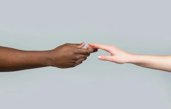 Hand skin colors touch two. Woman and African American man touching hands. White Caucasian female hands and black African American holding fingers together. World unity and racial love and races.
